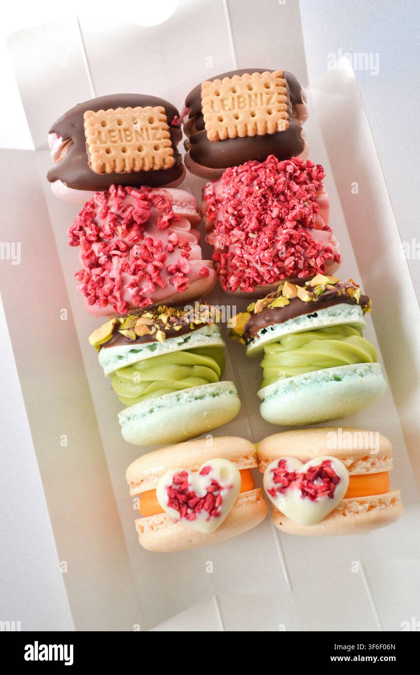 Set di fatcarons coreani gourmet con biscotti, pistacchio e decorazione a forma di cuore in una lunga scatola bianca Foto Stock