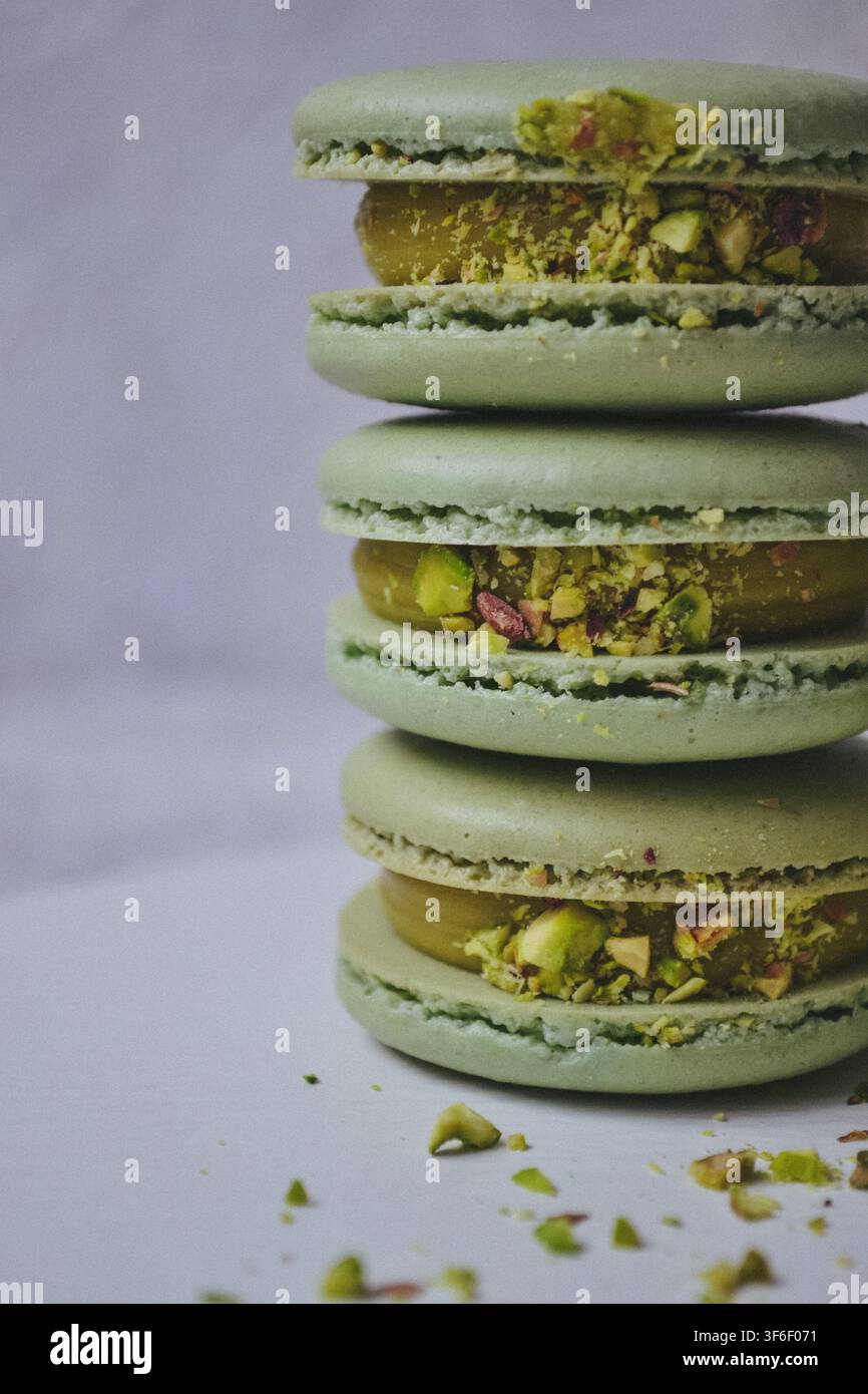 Pila di macaroncini ai pistacchi verdi con crema al burro e pistacchi tritati in primo piano Foto Stock