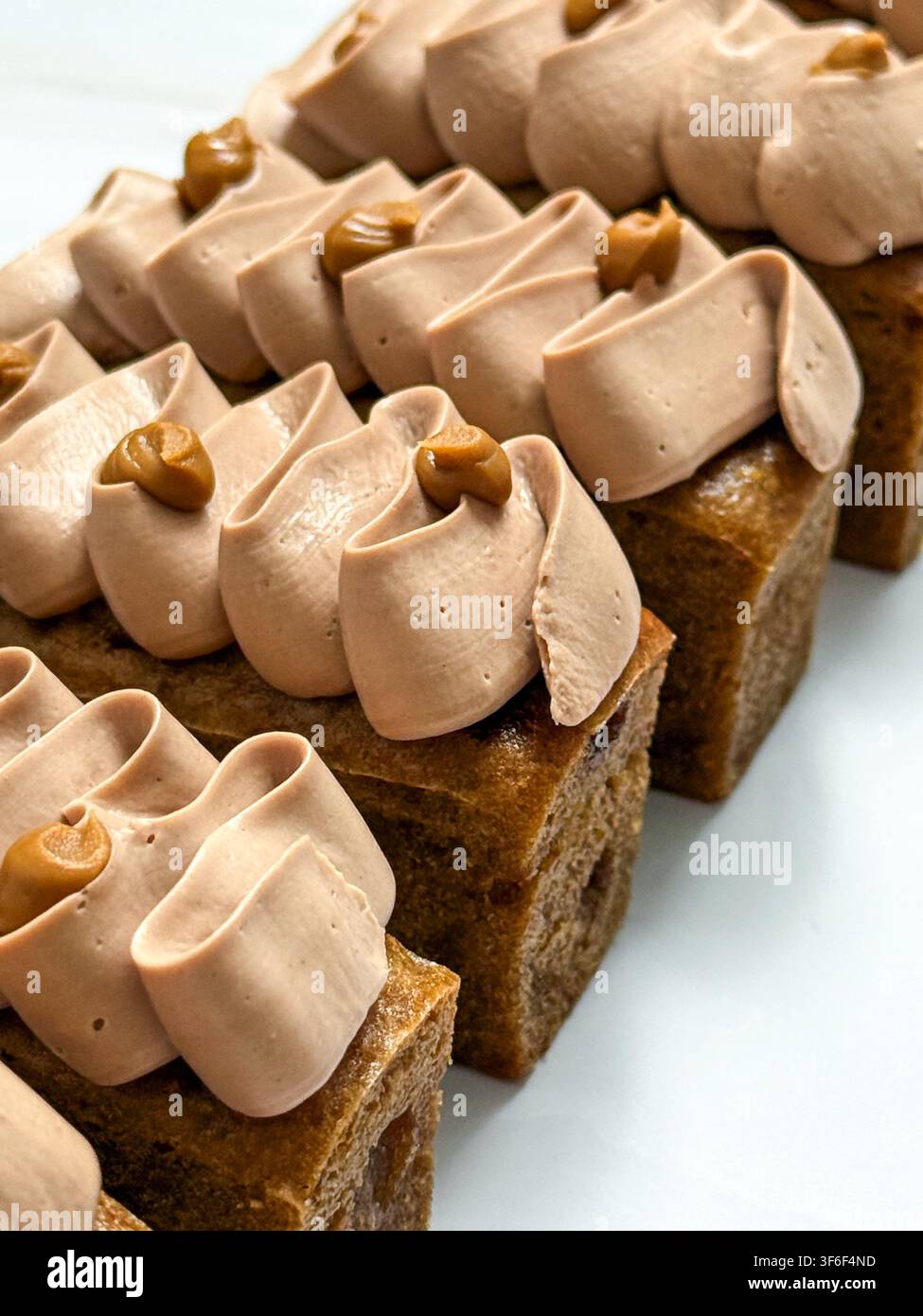 Eleganti mini panini decorati con onde di crema al cioccolato, gocce di caramello e briciole croccanti Foto Stock