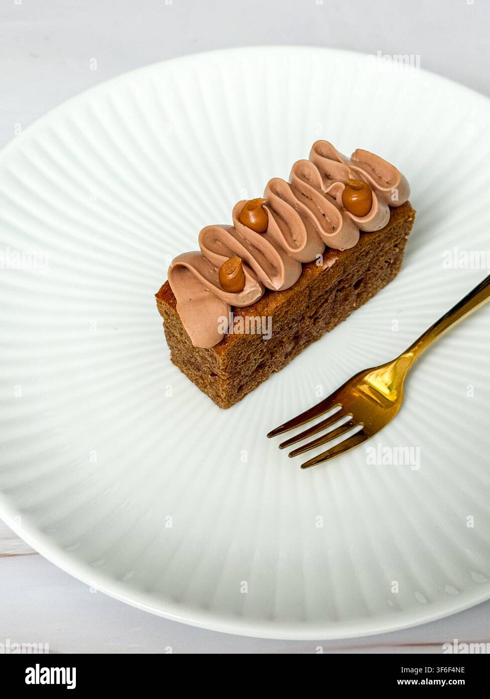 Eleganti mini panini decorati con onde di crema al cioccolato, gocce di caramello e briciole croccanti Foto Stock