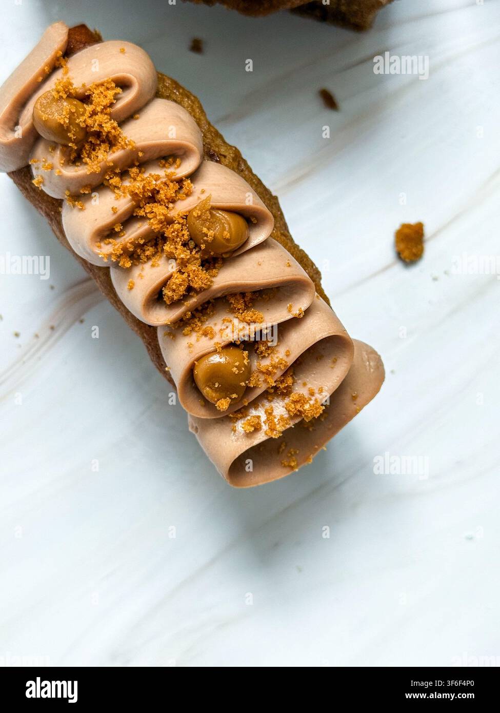 Eleganti mini panini decorati con onde di crema al cioccolato, gocce di caramello e briciole croccanti Foto Stock