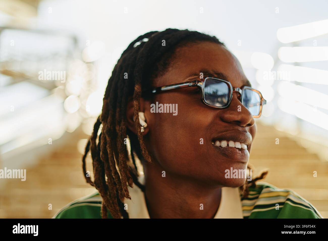 Uomo nero sorridente con occhiali da sole che ascolta musica all'aperto Foto Stock