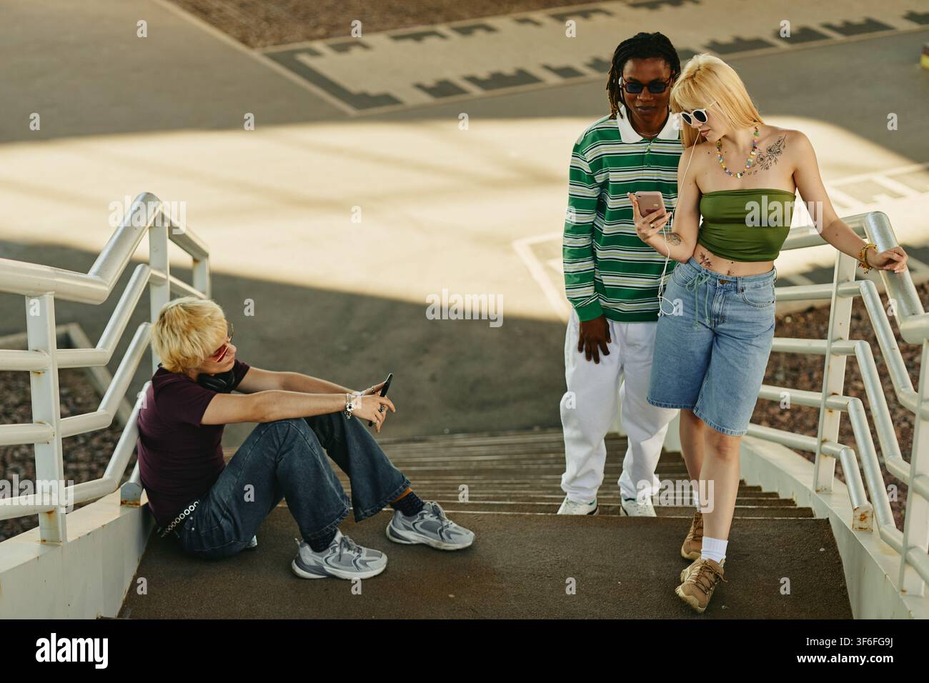 Diverse persone che utilizzano smartphone all'aperto sulle scale Foto Stock