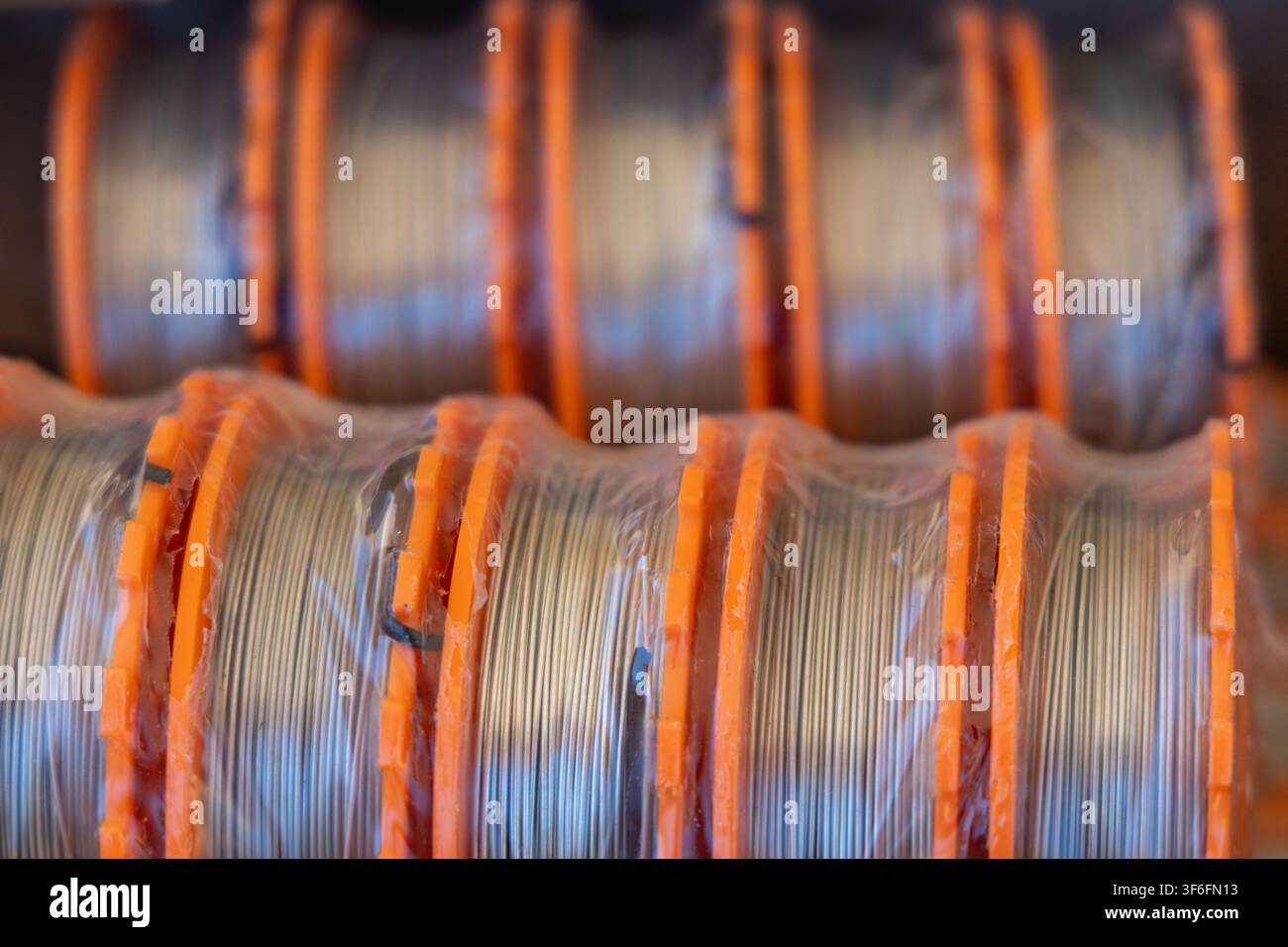 Prima vista di più bobine di filo sottile, ognuna fissata con separatori di plastica arancione e involucro protettivo trasparente Foto Stock