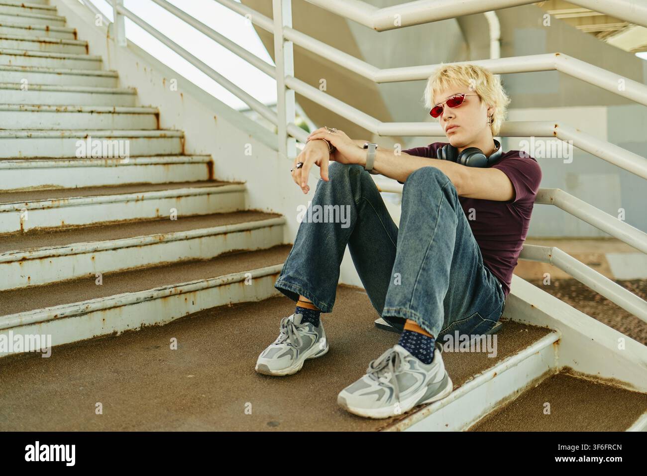 Uomo seduto sulle scale esterne che si rilassa dopo le lezioni del college Foto Stock