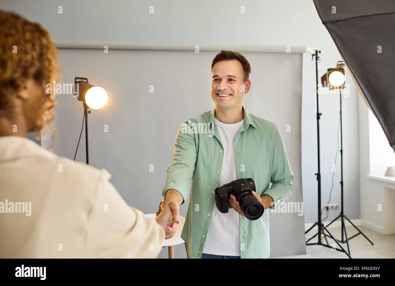 Stringata amichevole tra fotografo e modella in studio con illuminazione della fotocamera Foto Stock