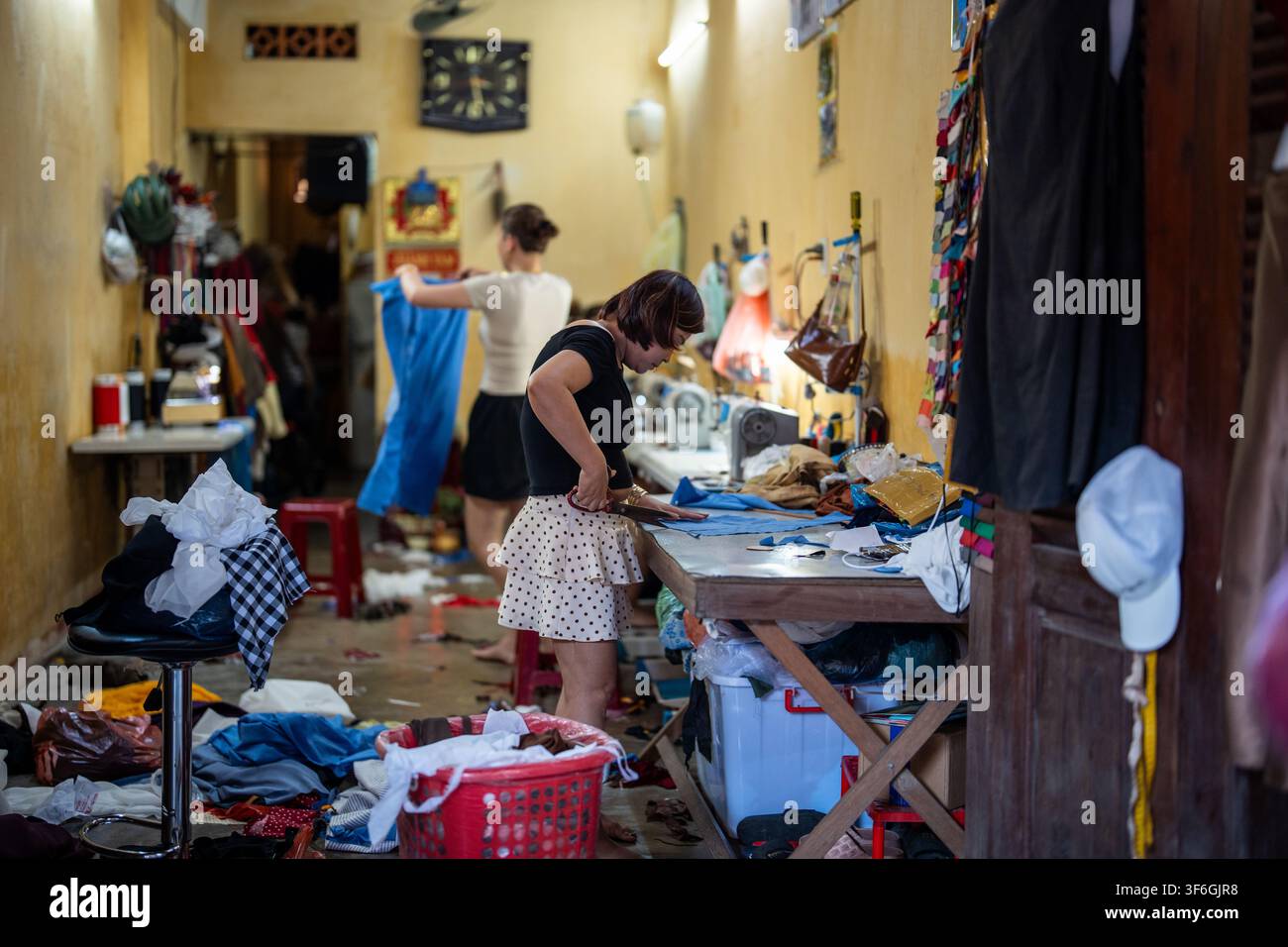 Processo di lavoro creativo in un atelier di cucito privato, sarta professionista che taglia il tessuto. Foto Stock