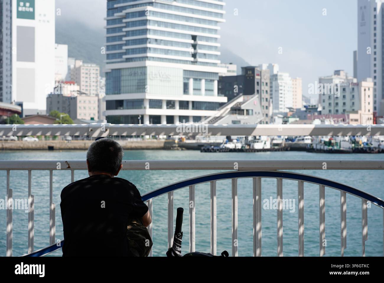 Un uomo anziano passa del tempo da solo sul lungomare di Busan Foto Stock