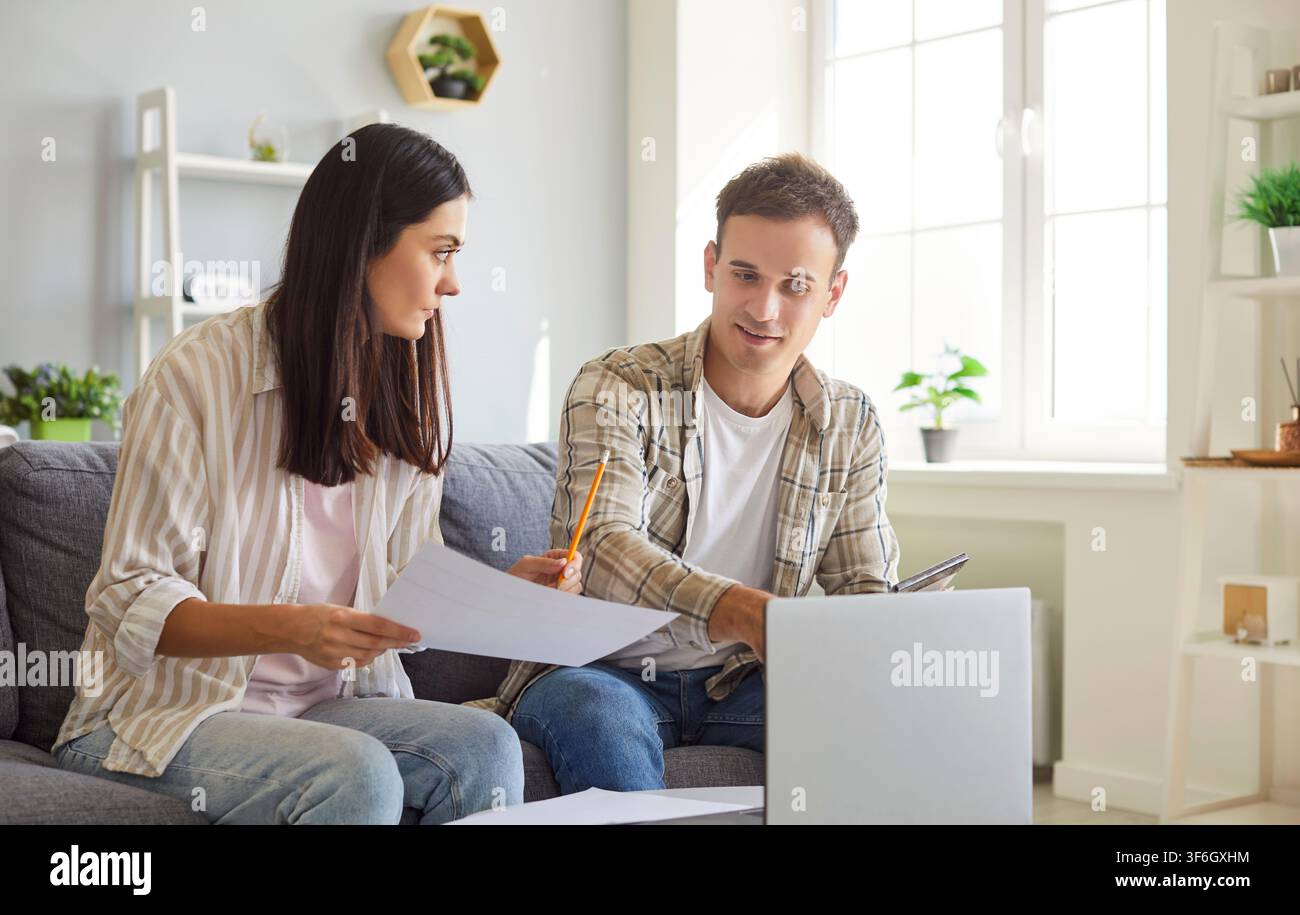 Coppia familiare che lavora su un laptop e gestisce finanze e investimenti a casa Foto Stock