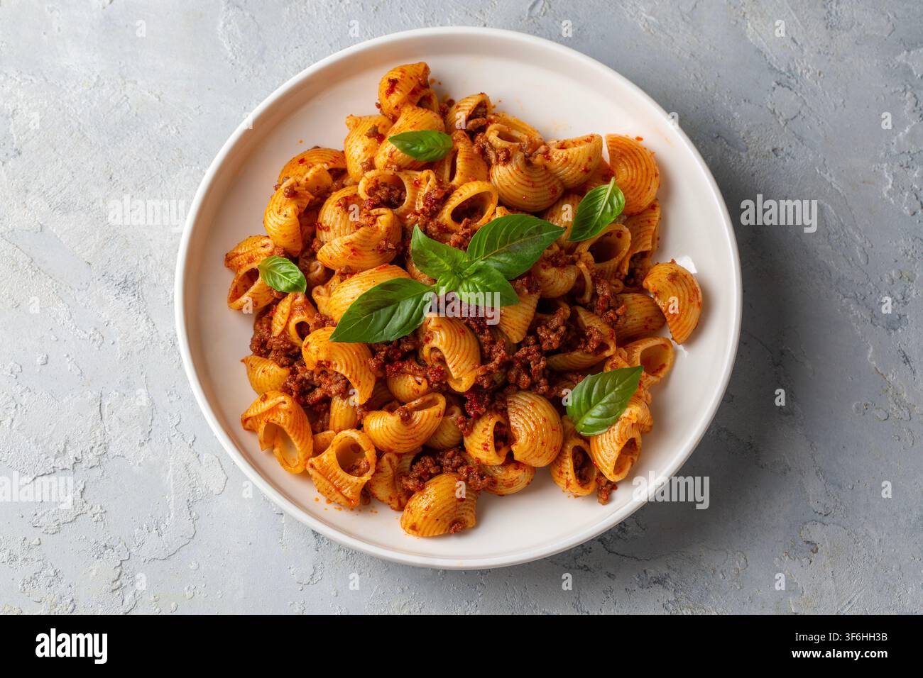 Pasta italiana Pipe Rigate con salsa bolognese e foglie di basilico fresco - Manti makarna Foto Stock