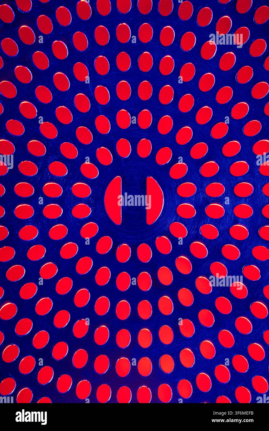 Un coperchio di scarico in una composizione astratta blu e rossa. Foto Stock