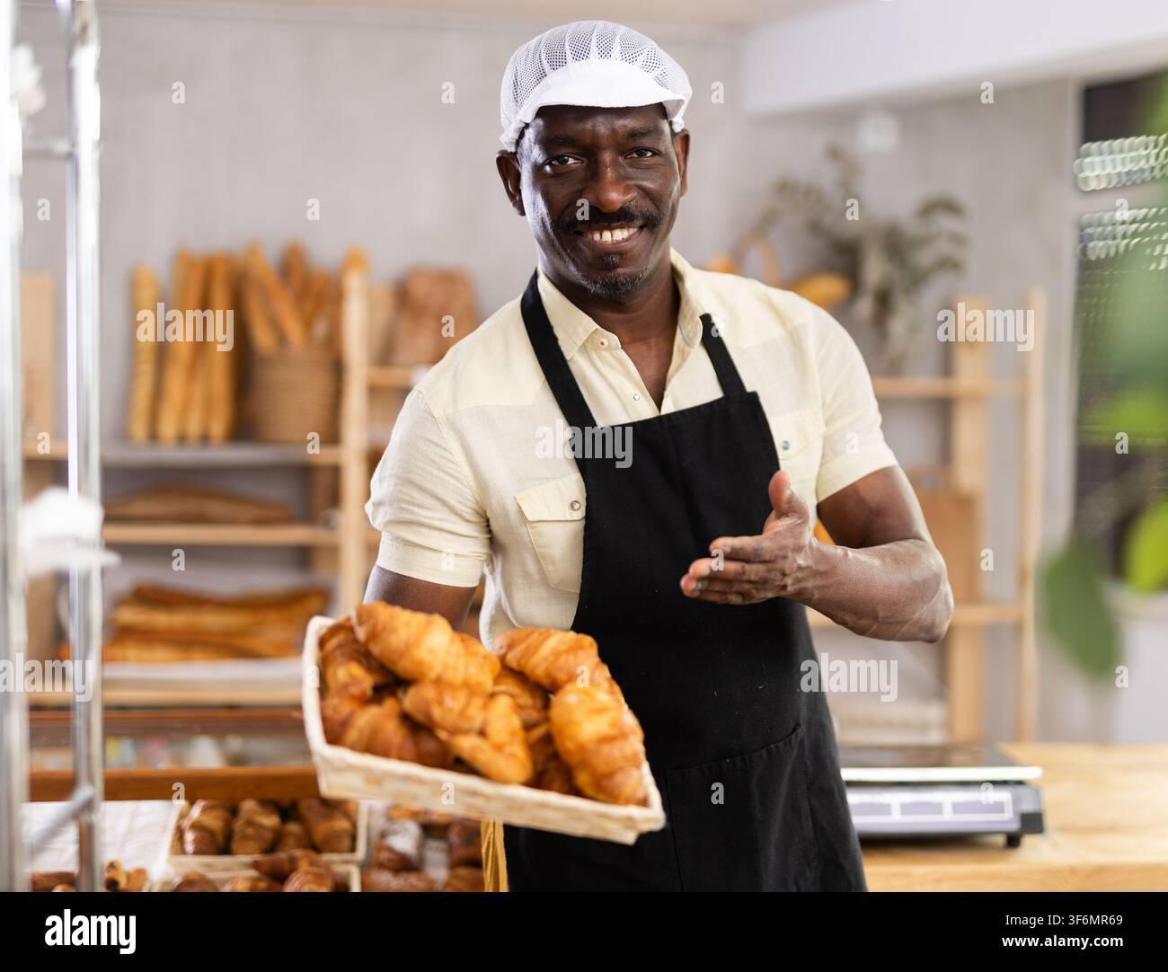 il panettiere sorridente offre l'acquisto di croissant caldi freschi Foto Stock