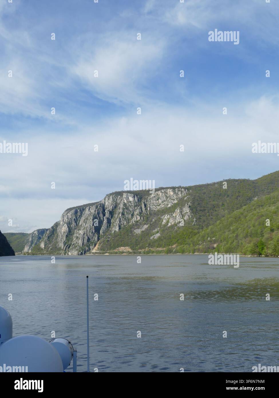 Fiume Danubio che scava attraverso la gola delle Porte di Ferro, Romania, con montagne boscose imponenti e scogliere rocciose sotto un cielo blu, acqua riflettente, showcase Foto Stock