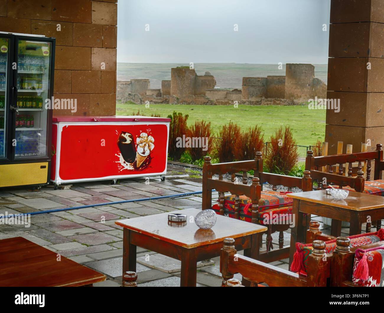 KARS, TURCHIA - 29 APRILE 2023 - Tavoli da caffè all'aperto e un congelatore per il ghiaccio accanto alle rovine storiche di Ani, che mostrano un contrasto tra il passato antico e il presente Foto Stock