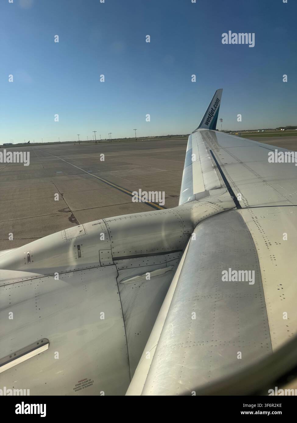 Vista verticale dal posto accanto al finestrino sull'ala e il motore di un aereo di linea sulla pista dell'aeroporto prima del decollo Foto Stock