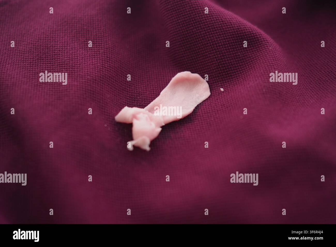 Vecchio pezzo di gomma da masticare su tessuto viola Foto Stock