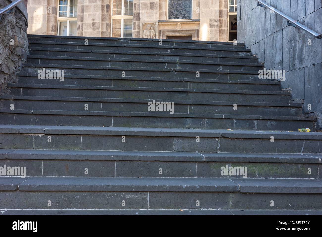 Si vedono scale che portano all'ingresso di un edificio in un luogo urbano. I gradini sono in pietra e mostrano segni di usura dovuti all'uso nel tempo. Foto Stock