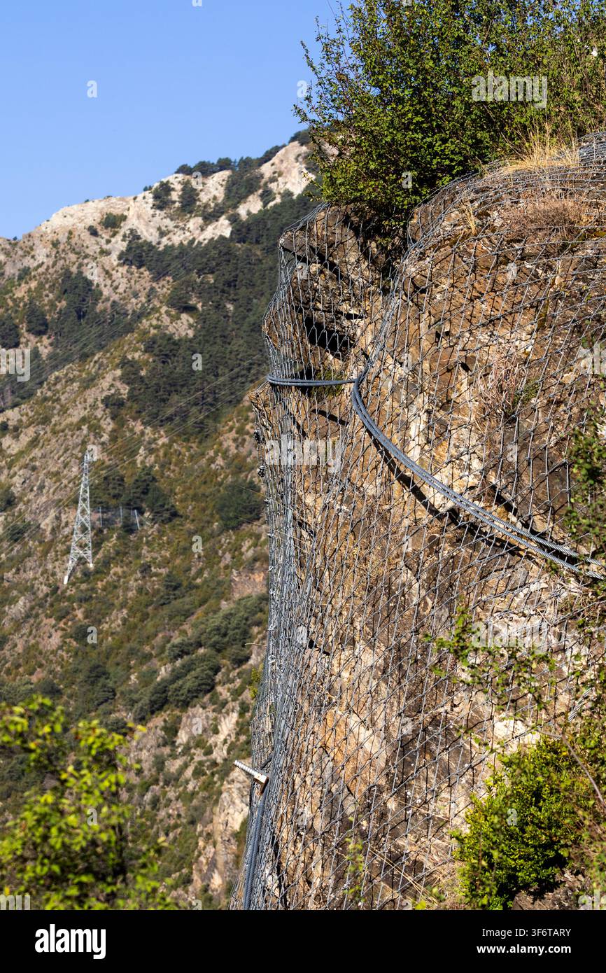 Rete metallica in acciaio installata su un pendio roccioso ripido per stabilizzare il terreno e ridurre il rischio di frane e smottamenti. L'immagine illustra un mod Foto Stock