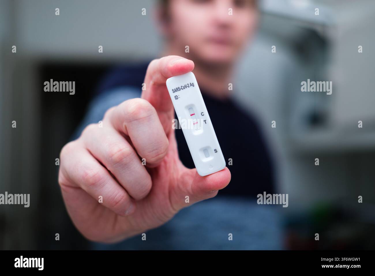 Mano che tiene una cassetta del test rapido per antigeni Sars-Cov-2 che mostra un risultato positivo Foto Stock