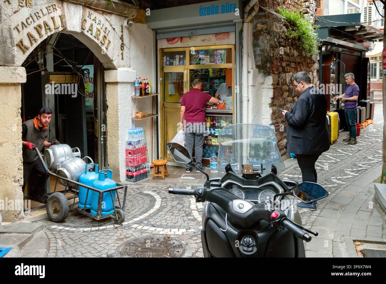 Il fattorino utilizza un piccolo ingresso laterale in un vicolo per uscire dal Grande Bazaar / Kapalıçarşı, nel distretto di Fatih, Istanbul, Turchia, Türkiye, Europa Foto Stock