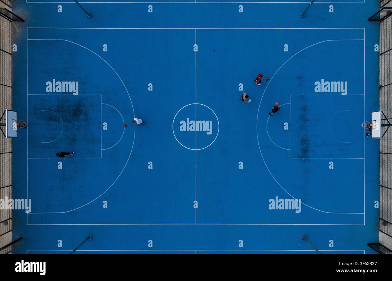 Vista aerea dall'alto di giocatori in competizione su un campo da basket blu completo all'aperto, gioco di basket di strada urbano e concetto sportivo. Foto Stock