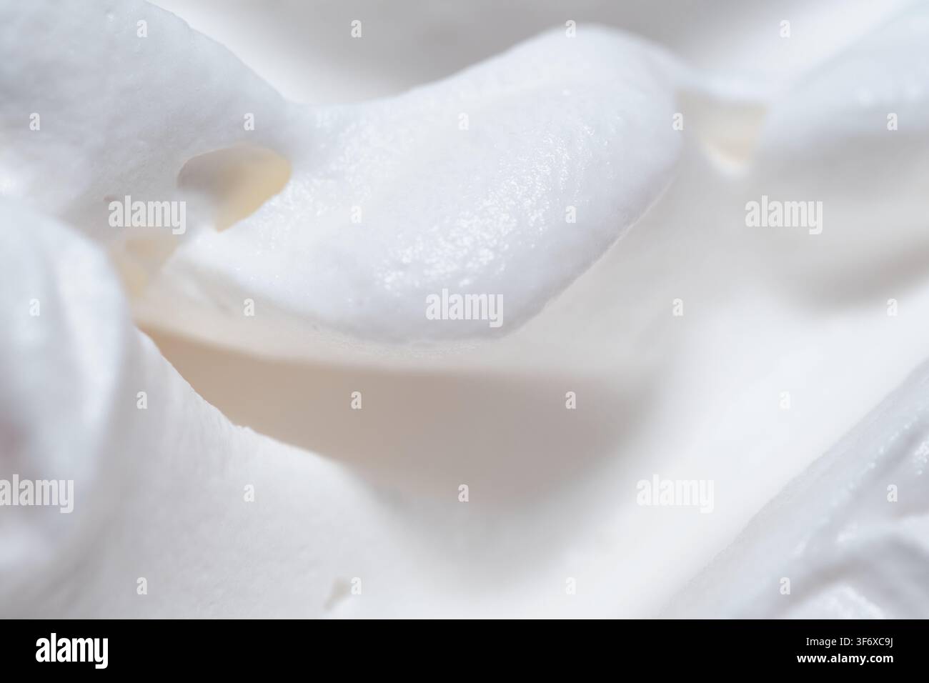 Vista estrema in primo piano di panna montata soffice che mostra picchi morbidi e lisci e vortici delicati con una ricca trama lattica. Foto Stock
