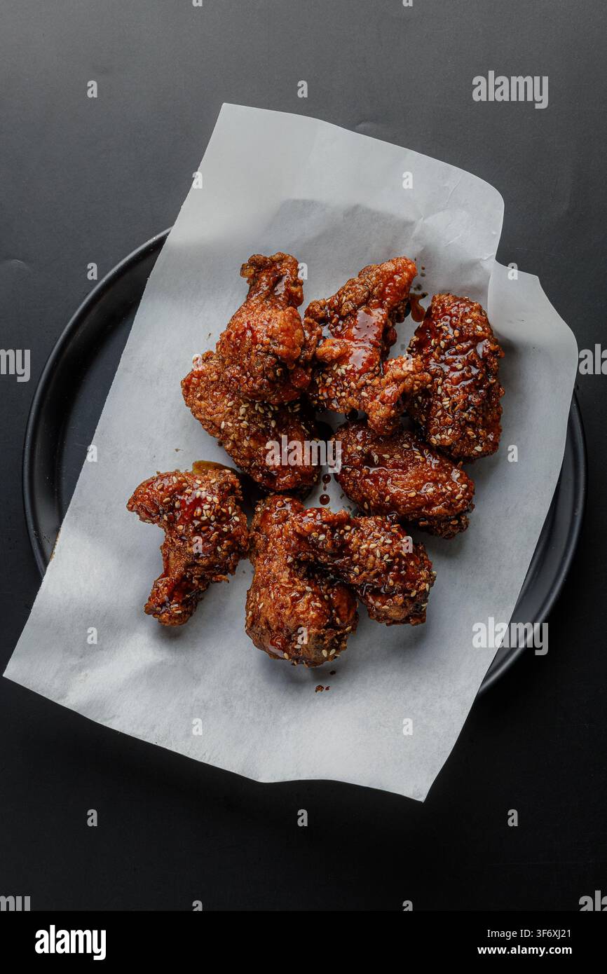 Deliziose ali di pollo fritte coreane su piatto nero Foto Stock