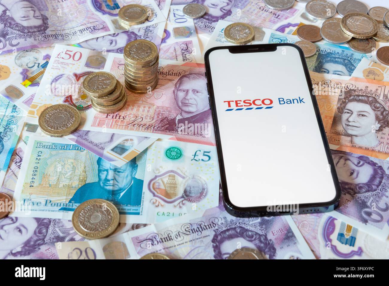 App di banking Tesco Bank con banconote e monete in sfondo Foto Stock