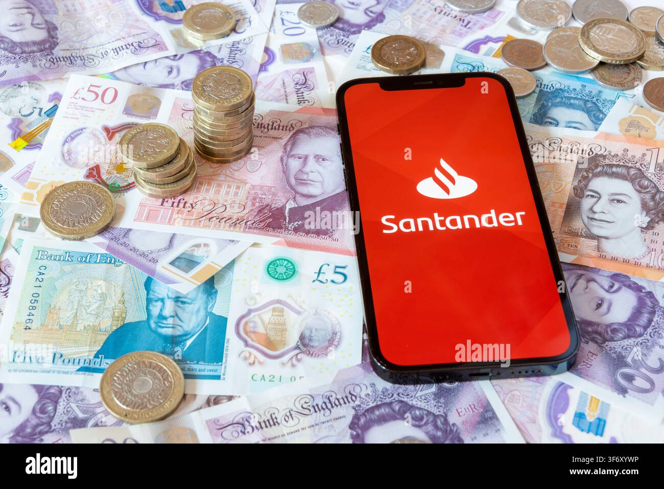 App di banking Santander con banconote e monete in sterline sullo sfondo Foto Stock