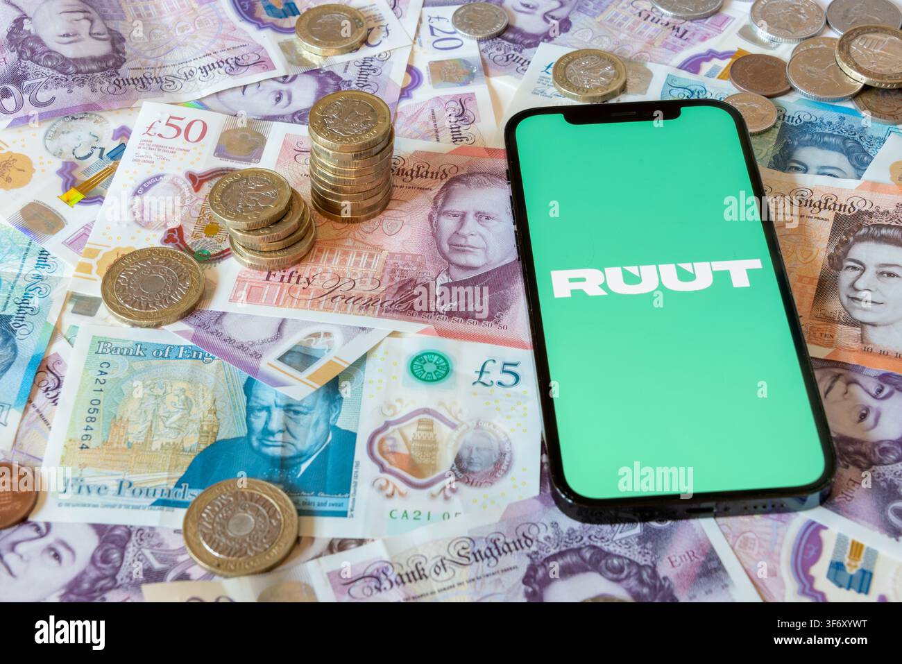 Applicazione bancaria Ruut con banconote e monete in sterline in sottofondo Foto Stock