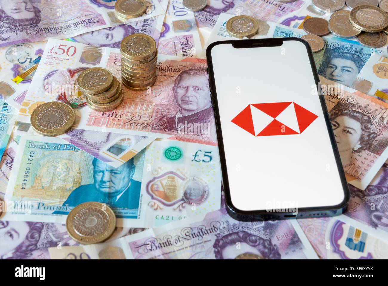 App di banking HSBC con banconote e monete in sterline in sottofondo Foto Stock