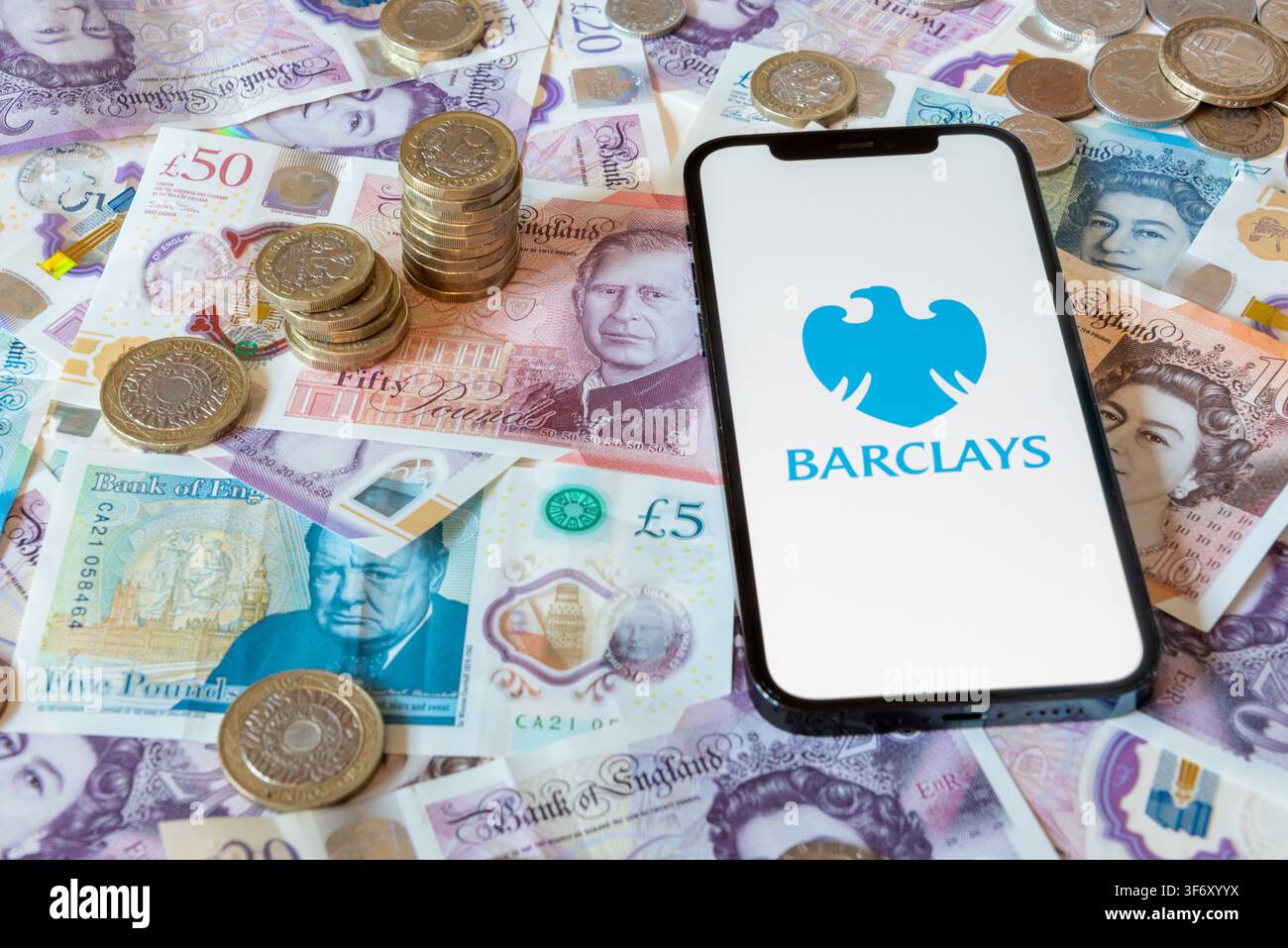App di banking Barclays con banconote e monete in sterline sullo sfondo Foto Stock
