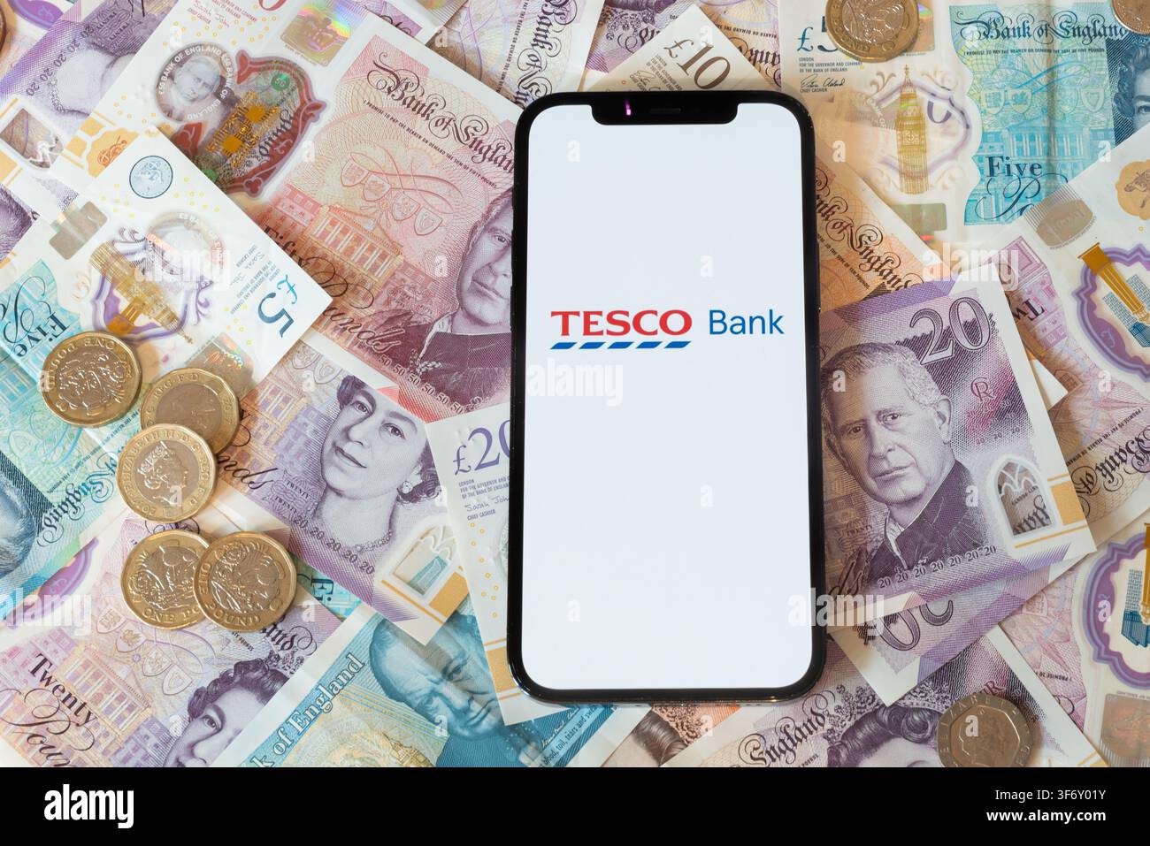 App di banking Tesco Bank con banconote e monete in sfondo Foto Stock