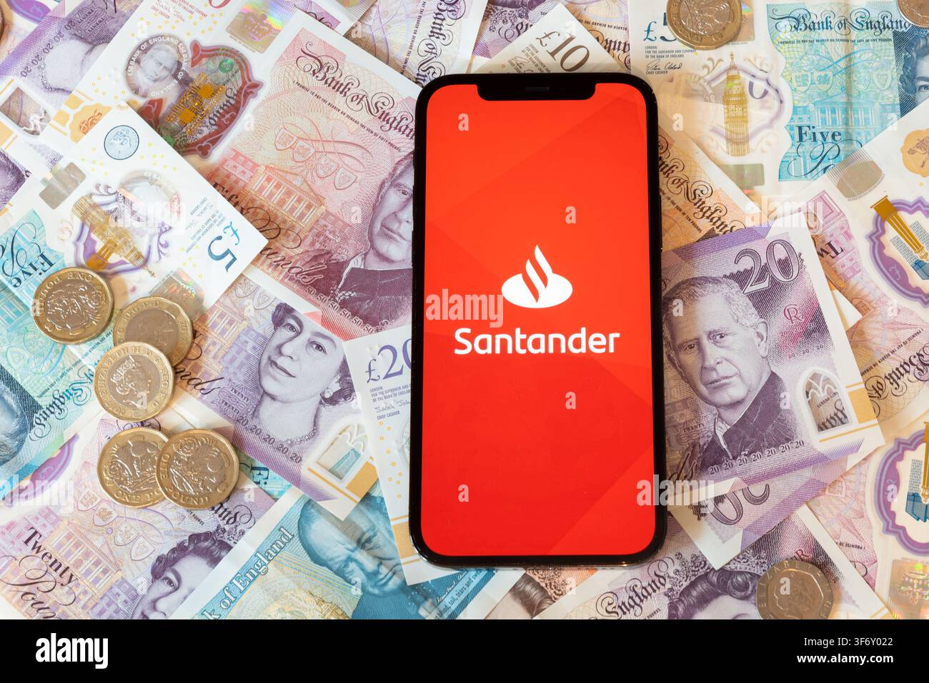 App di banking Santander con banconote e monete in sterline sullo sfondo Foto Stock