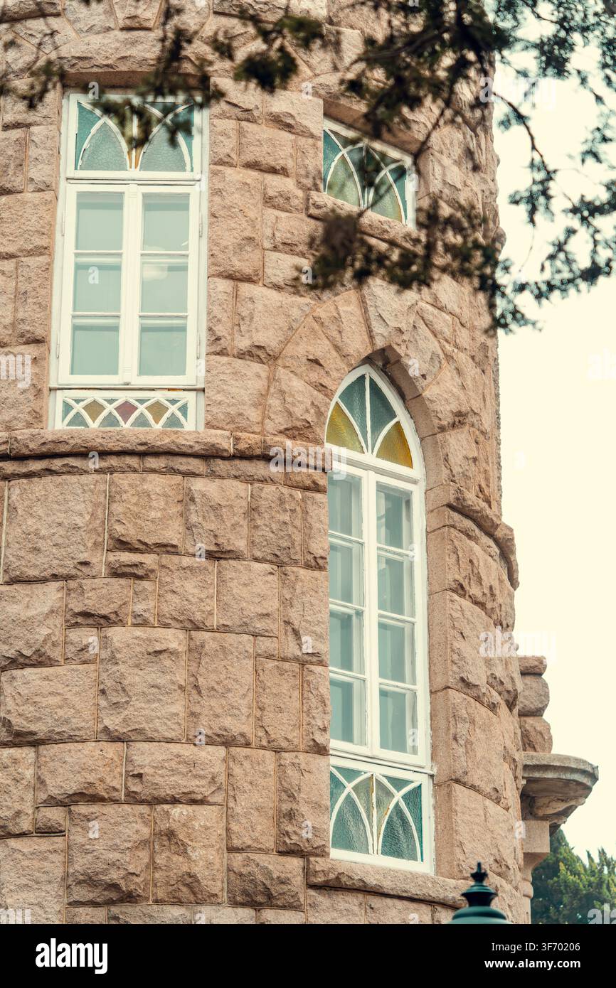 Finestre di vetro colorato gotiche sulla torre in granito del castello di Huashi Lou, Badaguan, Qingdao, Cina Foto Stock