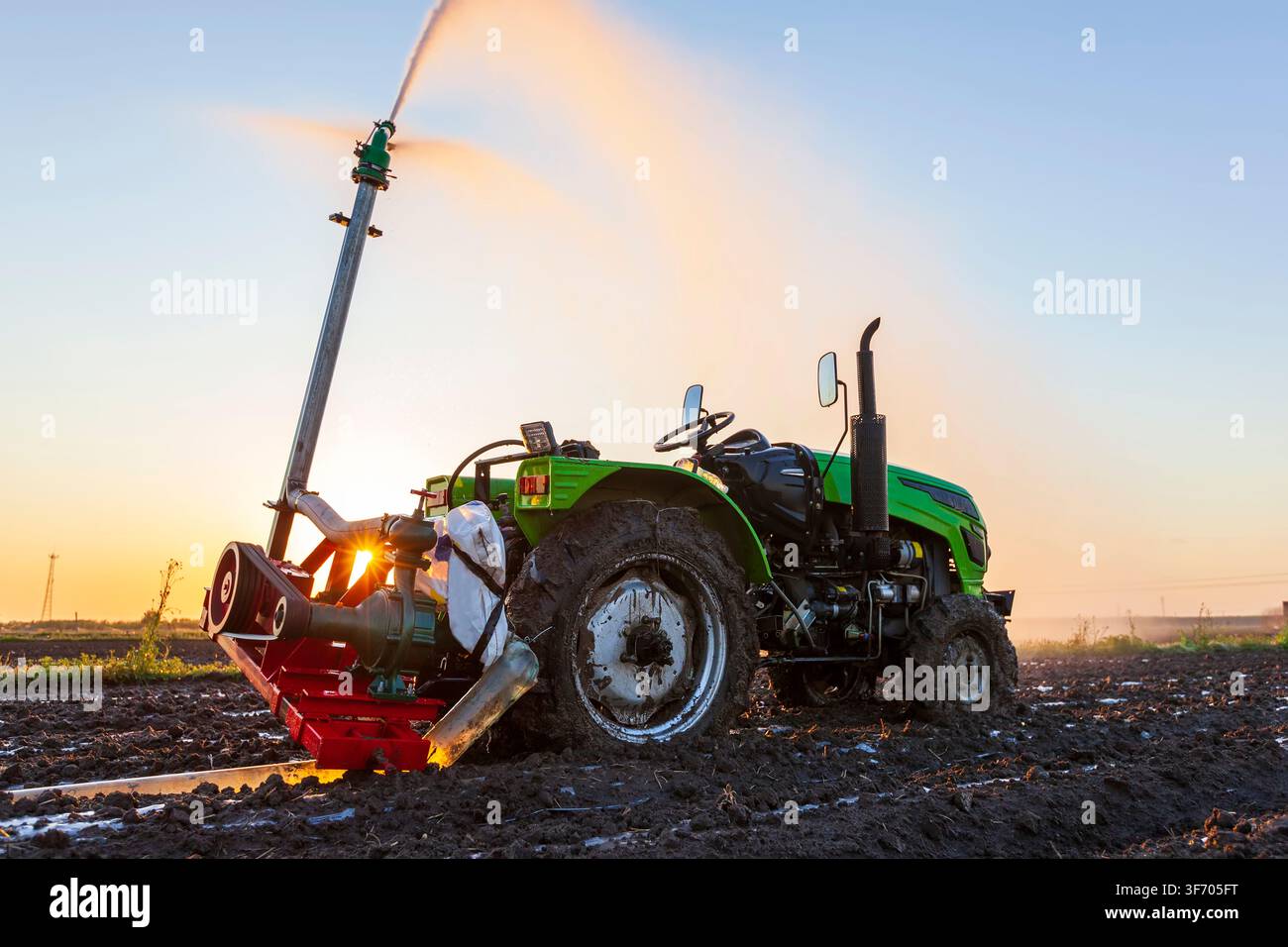 La sera, i trattori irrigano i campi Foto Stock