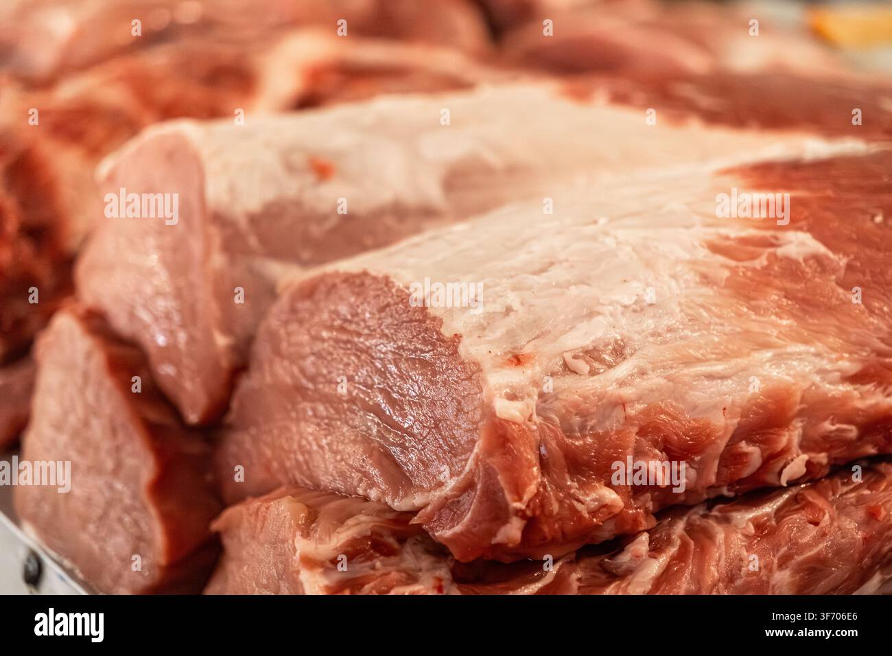Vista ravvicinata di fette di carne di maiale non trasformate disposte per la vendita in un negozio, offrendo una visione dettagliata delle fibre muscolari e del grasso per i professionisti del cibo Foto Stock