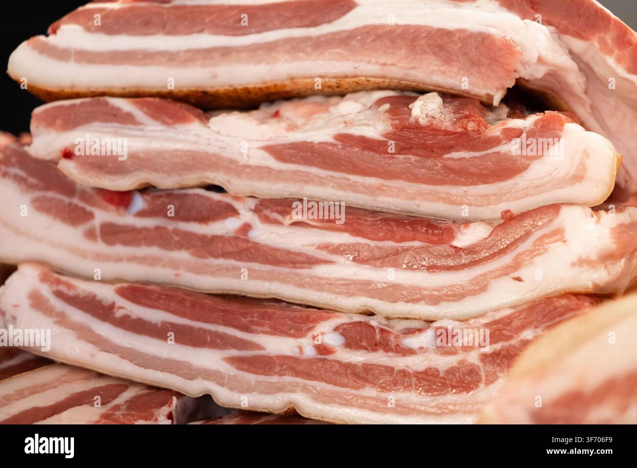 Close up di fette di pancetta cruda impilate che evidenziano la ricca trama e la marmorizzazione della carne fresca, perfetta per contenuti culinari, marchio di ristorante Foto Stock