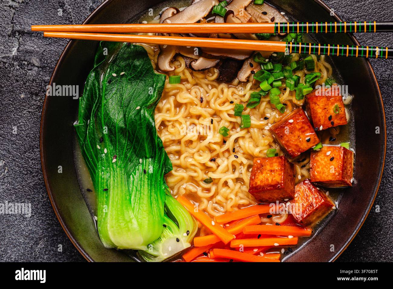 Zuppa miso ramen con noodles servita con tofu, bok choy, carote e funghi in una ciotola. Foto Stock