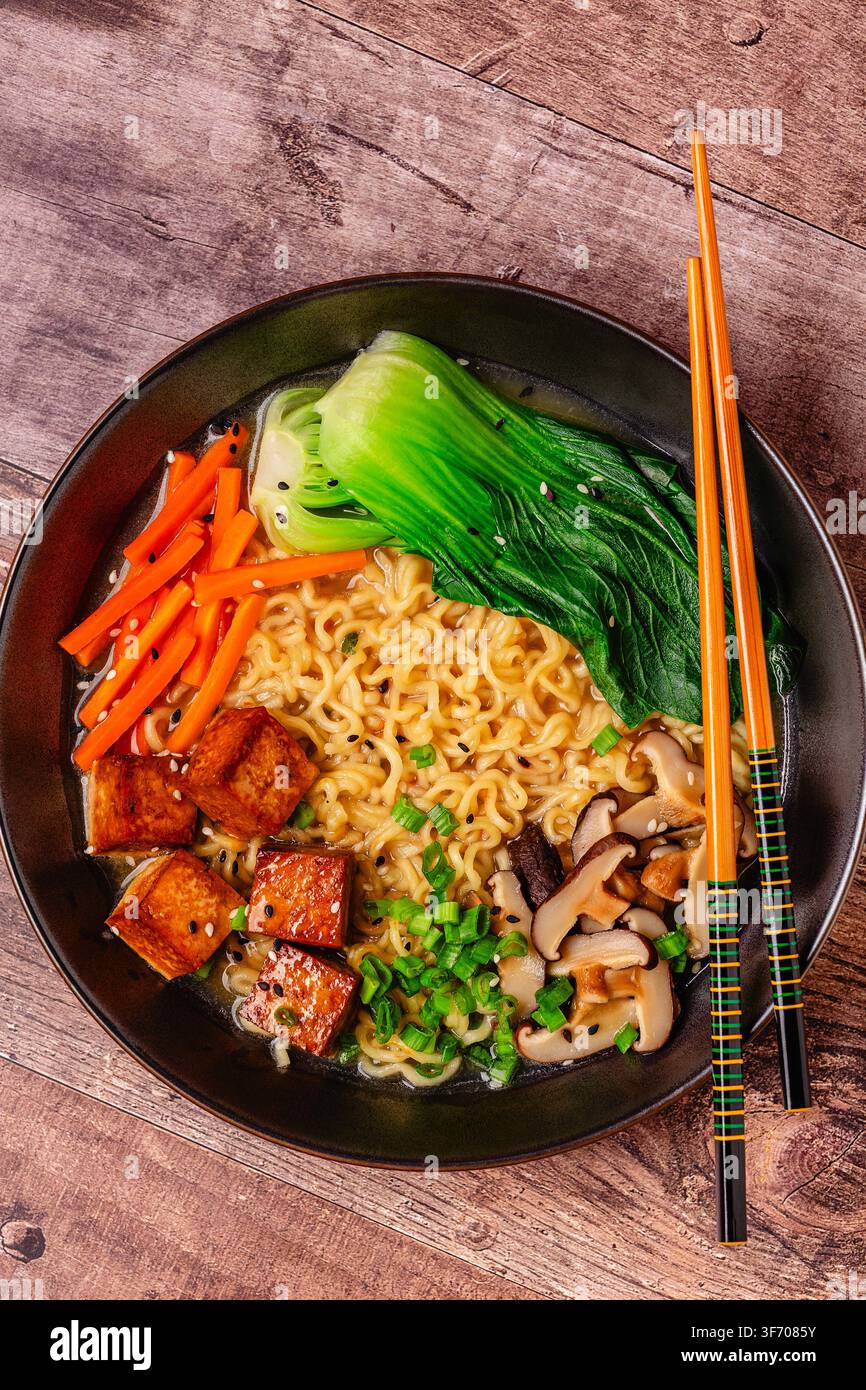 Zuppa miso ramen con noodles servita con tofu, bok choy, carote e funghi in una ciotola. Foto Stock