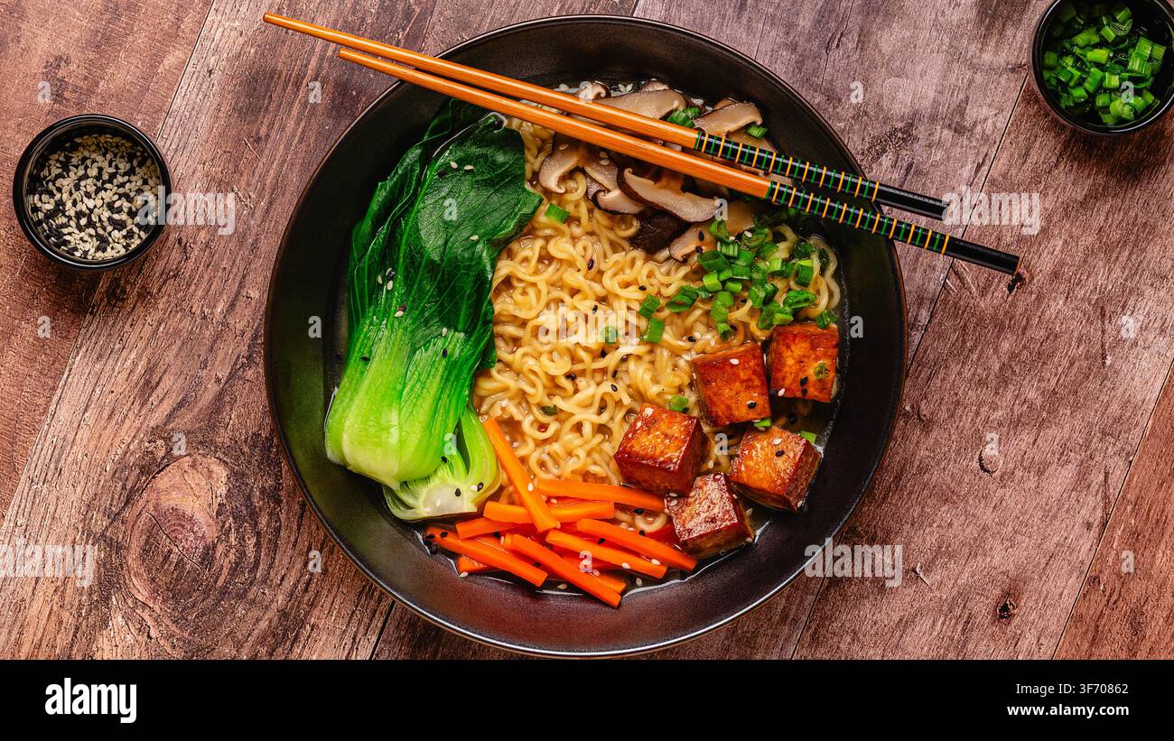 Zuppa miso ramen con noodles servita con tofu, bok choy, carote e funghi in una ciotola. Foto Stock