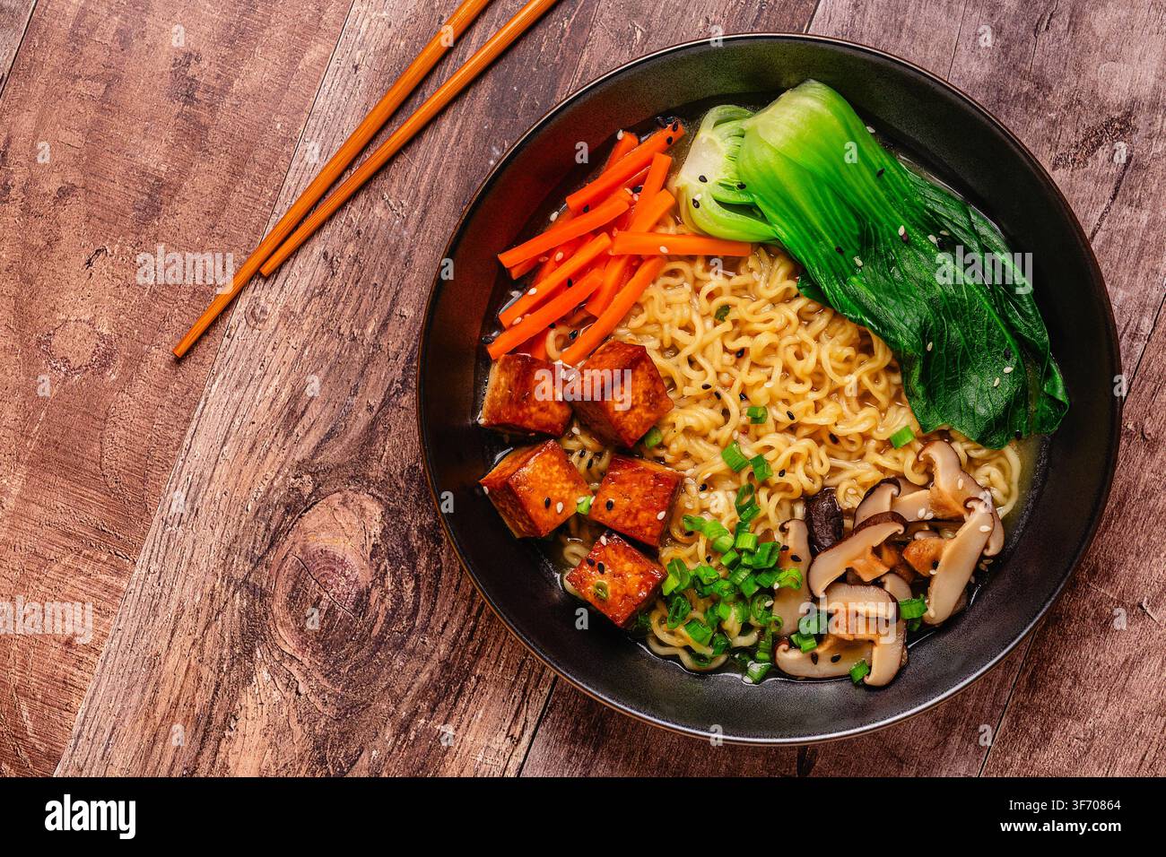 Zuppa miso ramen con noodles servita con tofu, bok choy, carote e funghi in una ciotola. Foto Stock