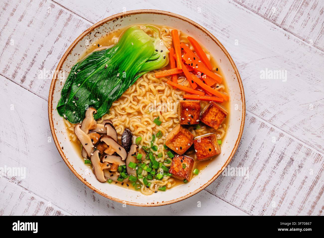 Zuppa miso ramen con noodles servita con tofu, bok choy, carote e funghi in una ciotola. Foto Stock