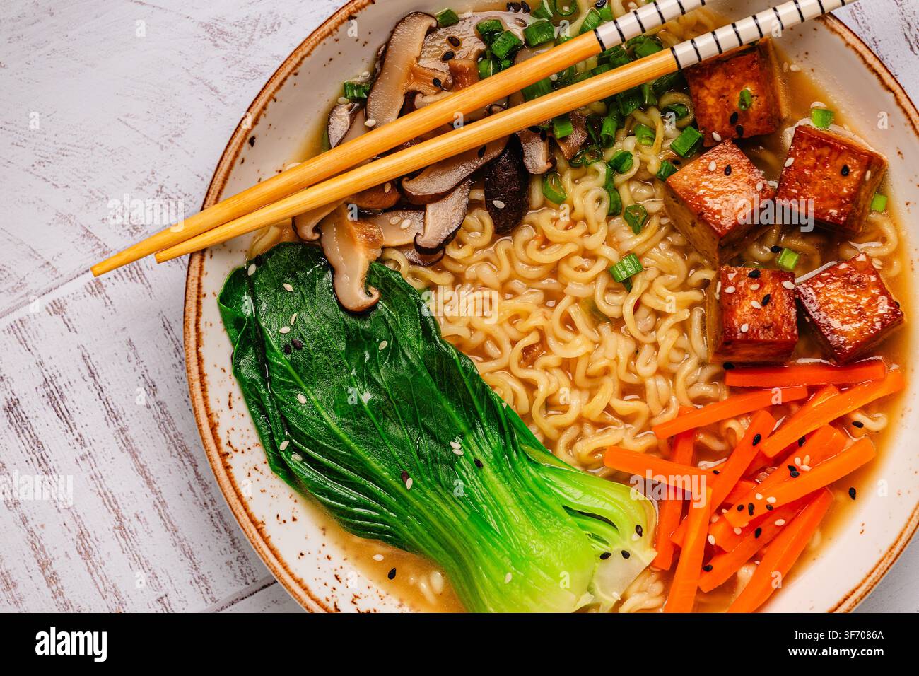 Zuppa miso ramen con noodles servita con tofu, bok choy, carote e funghi in una ciotola. Foto Stock