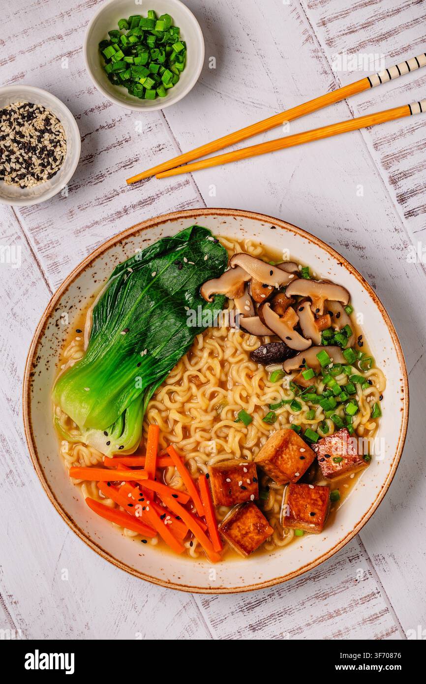 Zuppa miso ramen con noodles servita con tofu, bok choy, carote e funghi in una ciotola. Foto Stock