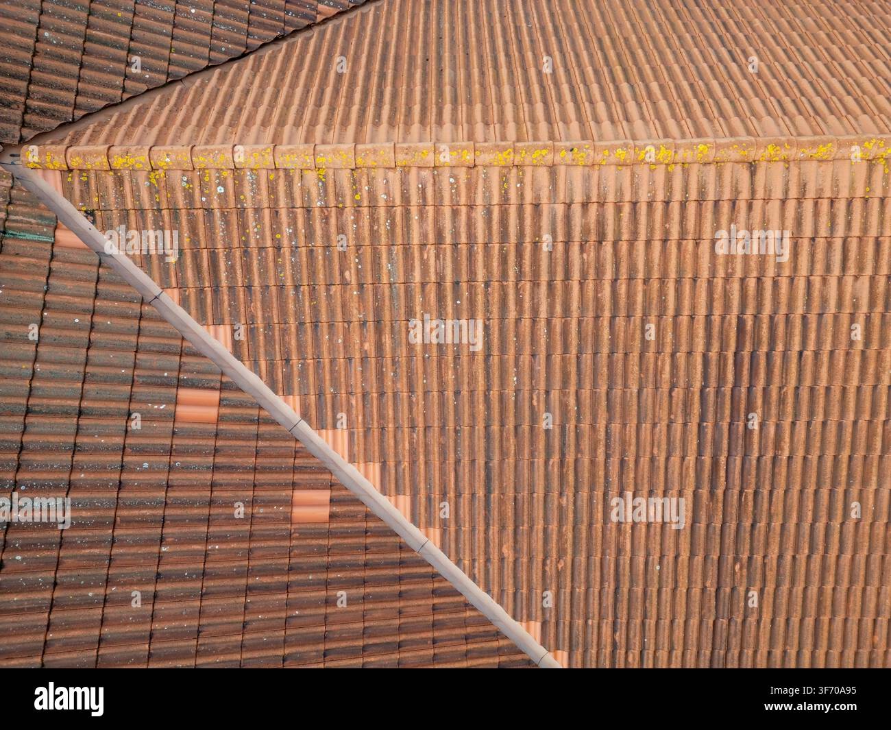 Vista aerea di tegole di tetto in argilla marrone con macchie di lichene giallo e linee geometriche del tetto a Kempele, Ostrobotnia settentrionale, Finlandia. Foto Stock