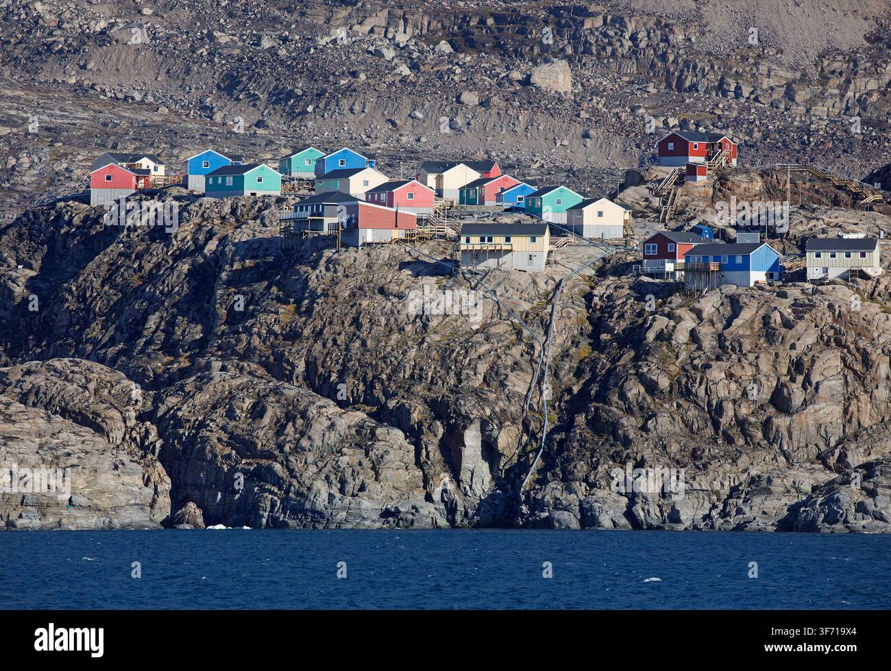 Case colorate costruite sulla costa rocciosa di Uummannaq, una remota città artica su un'isola nel fiordo di Uummannaq, nella Groenlandia occidentale Foto Stock