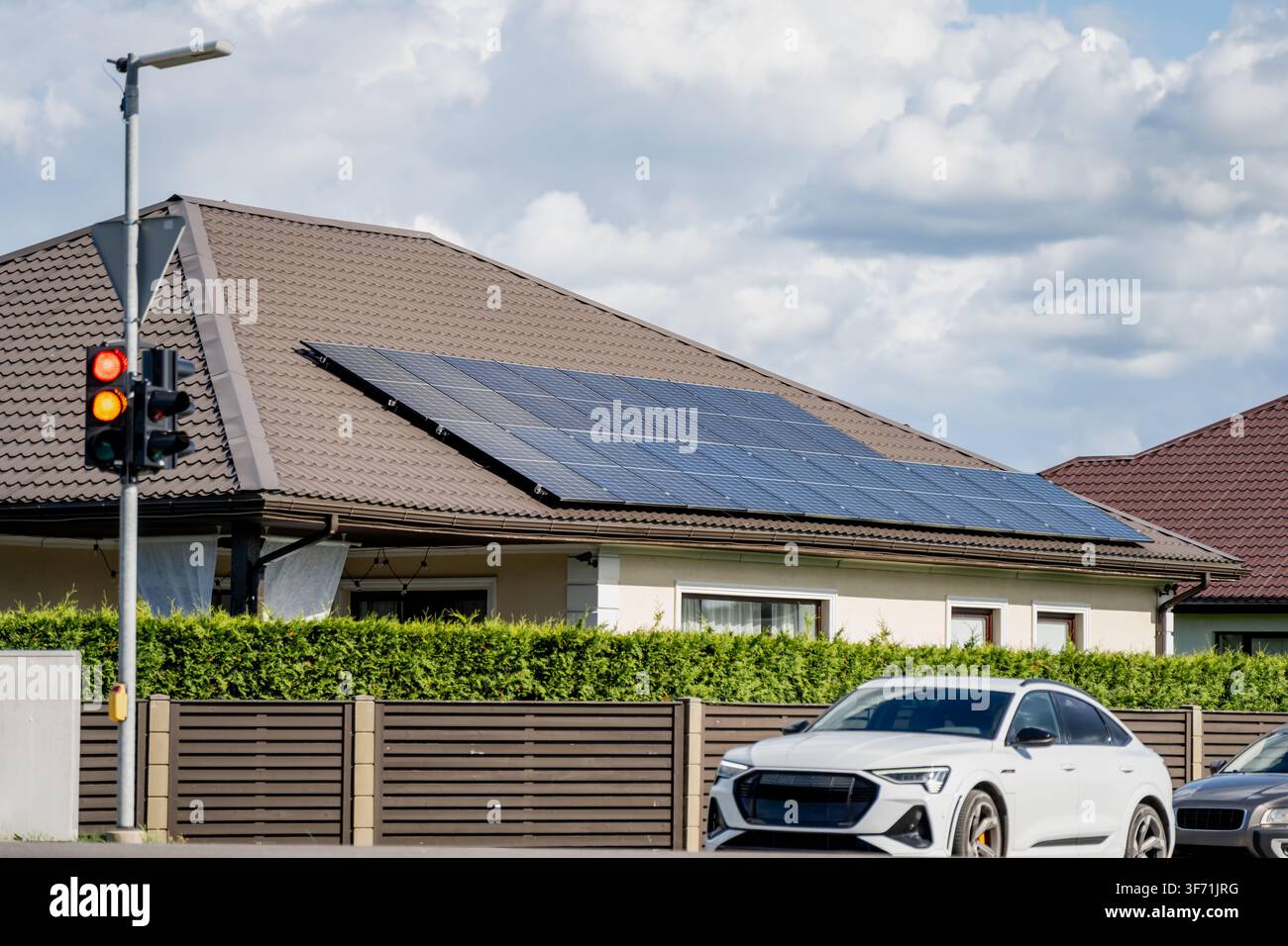 Proprietà residenziale privata con pannelli solari fotovoltaici sul tetto, semaforo stradale e veicolo elettrico moderno Foto Stock