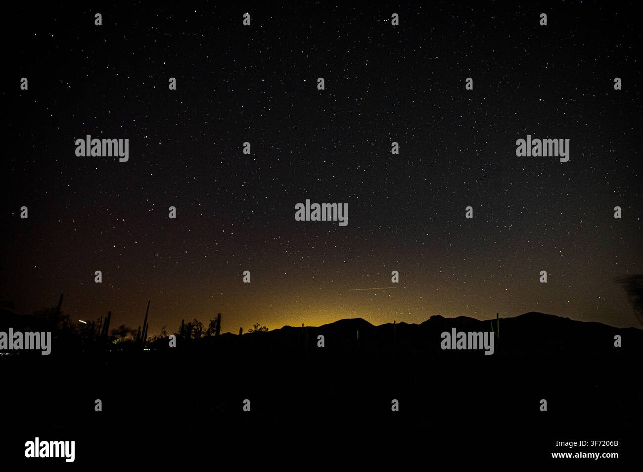 Un campo fitto di stelle riempie il cielo notturno sopra una cresta montuosa in silhouette nel deserto del Sonora, in Arizona. Foto Stock