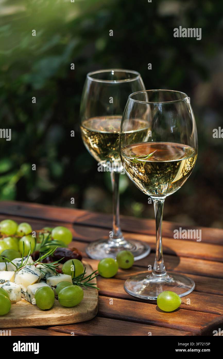Prima vista di bicchieri di vino bianco con uva e formaggio all'aperto Foto Stock